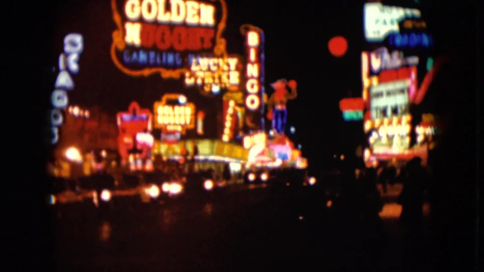 1961 Nevada 8mm frame showing Golden Nugget and other neon signs glowing above blurred nighttime traffic.