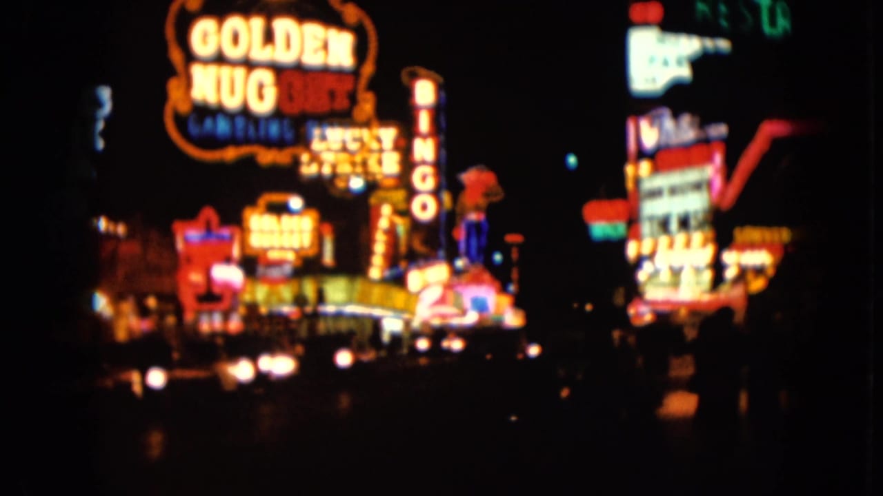 1961 Nevada home-movie frame with Golden Nugget signage, vertical bingo lettering, and blurred neon storefronts at night.