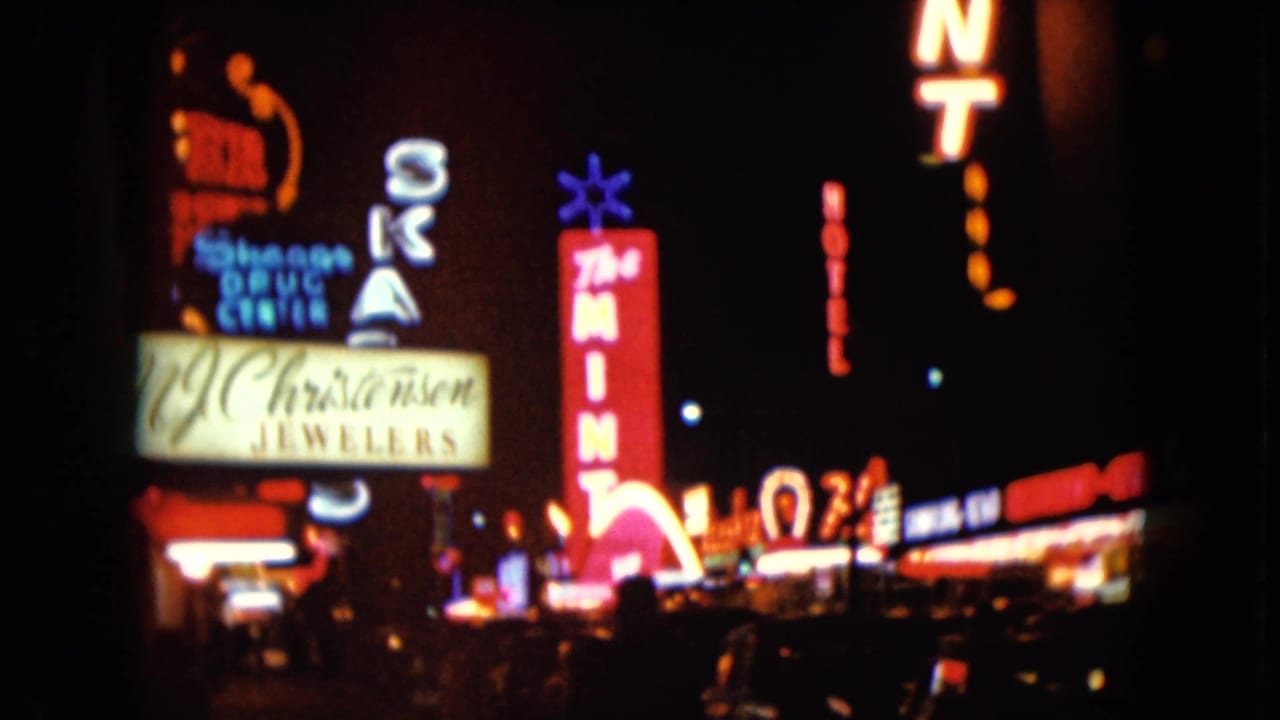 1961 Nevada night street view with glowing neon signs for The Mint, Christensen Jewelers, and nearby businesses.