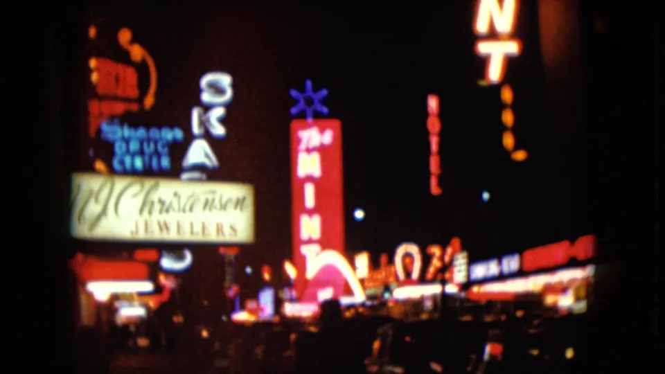 1961 Nevada night street view with glowing neon signs for The Mint, Christensen Jewelers, and nearby businesses.