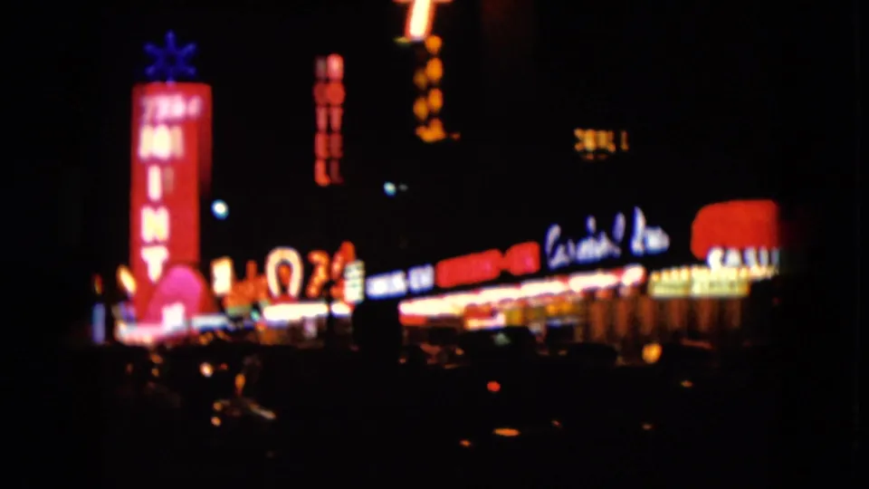 End frame of 1961 Nevada night footage with The Mint sign, glowing storefront signs, and silhouetted street activity.