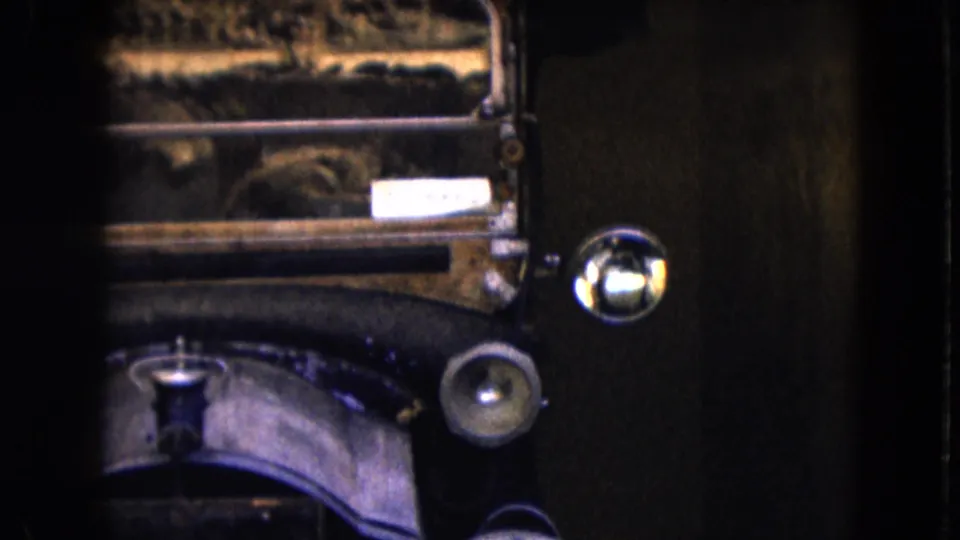 1961 Nevada home-movie frame with a tight view of an antique car's headlight, fender, and front bodywork.