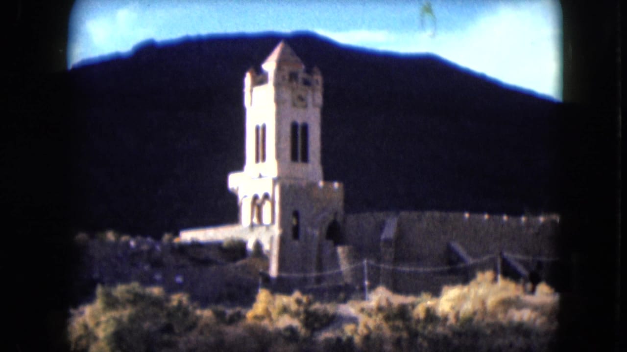 1961 Nevada 8mm view of Scotty's Castle tower and pale walls set against a shadowed mountain backdrop.