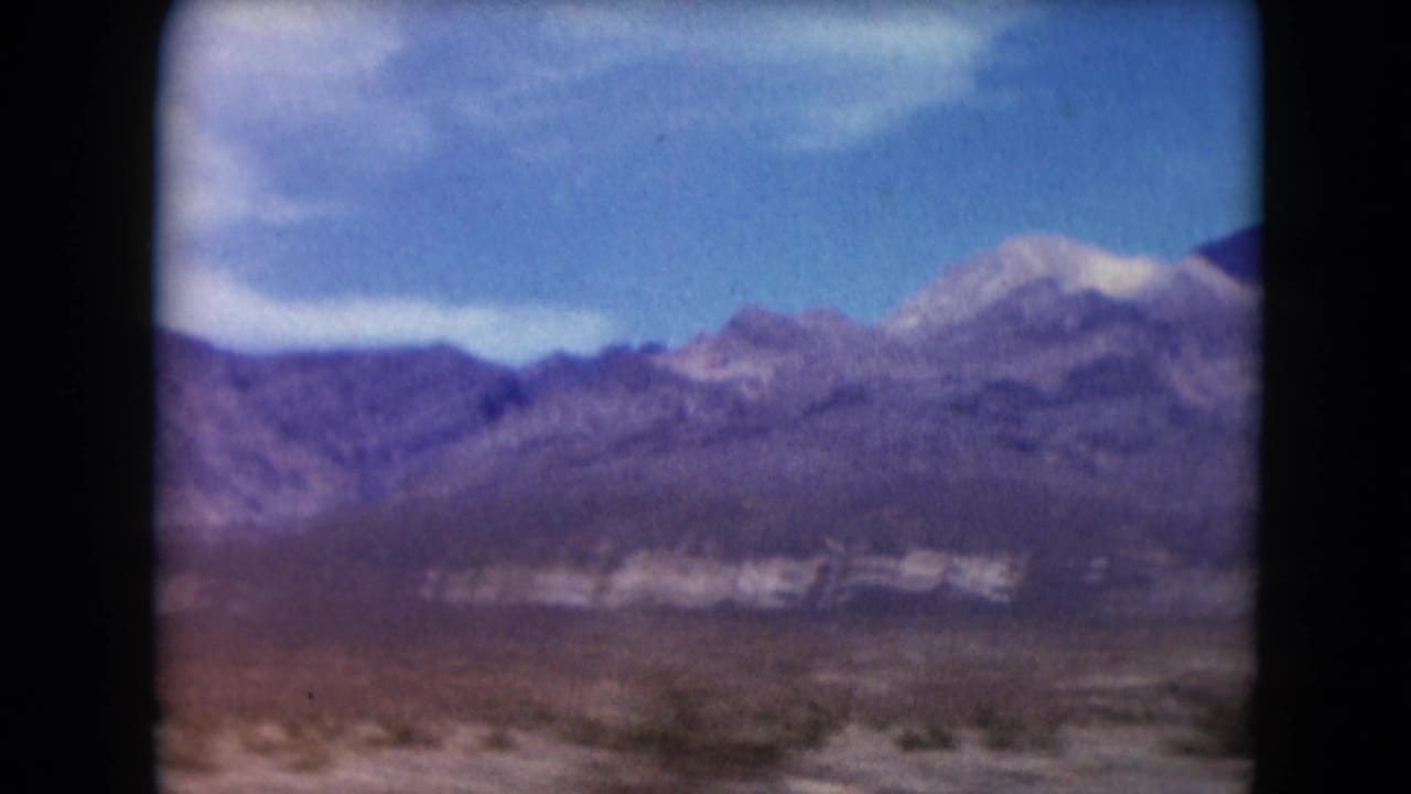 Distant mountain range beyond a desert plain under blue sky.