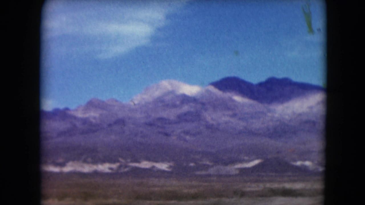 1961 Nevada travel view with purple-toned ridges, pale mountain bands, and open desert foreground.