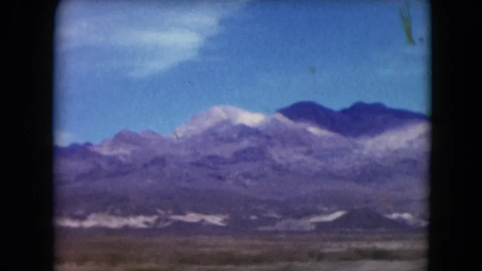 1961 Nevada travel view with purple-toned ridges, pale mountain bands, and open desert foreground.
