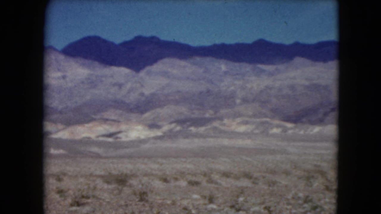 Desert brushland stretches toward pale hills and darker mountains.