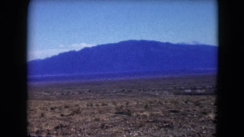 Nevada desert landscape from a 1961 8mm road trip, showing open plain and a broad mountain ridge.