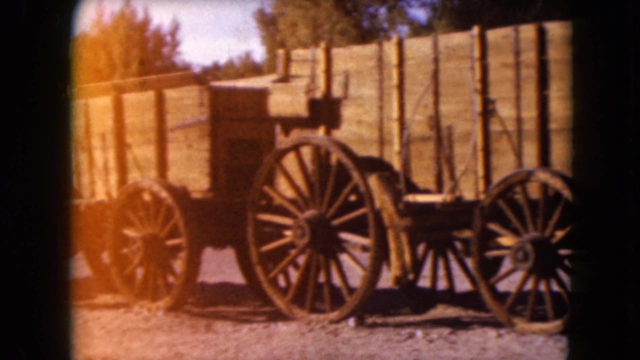 Two wooden wagons with large spoked wheels parked on gravel.