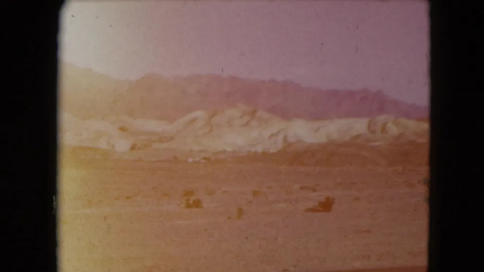 1961 Nevada frame showing open desert, sparse shrubs, pale ridges, and distant mountains in faded 8mm color.