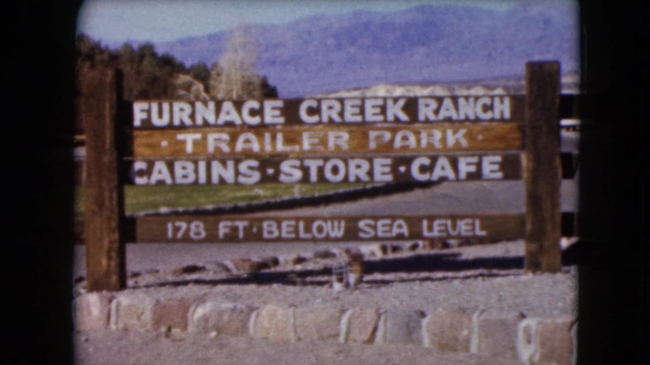 1961 8mm frame showing the Furnace Creek Ranch sign listing trailer park, cabins, store, cafe, and 178 feet below sea level.