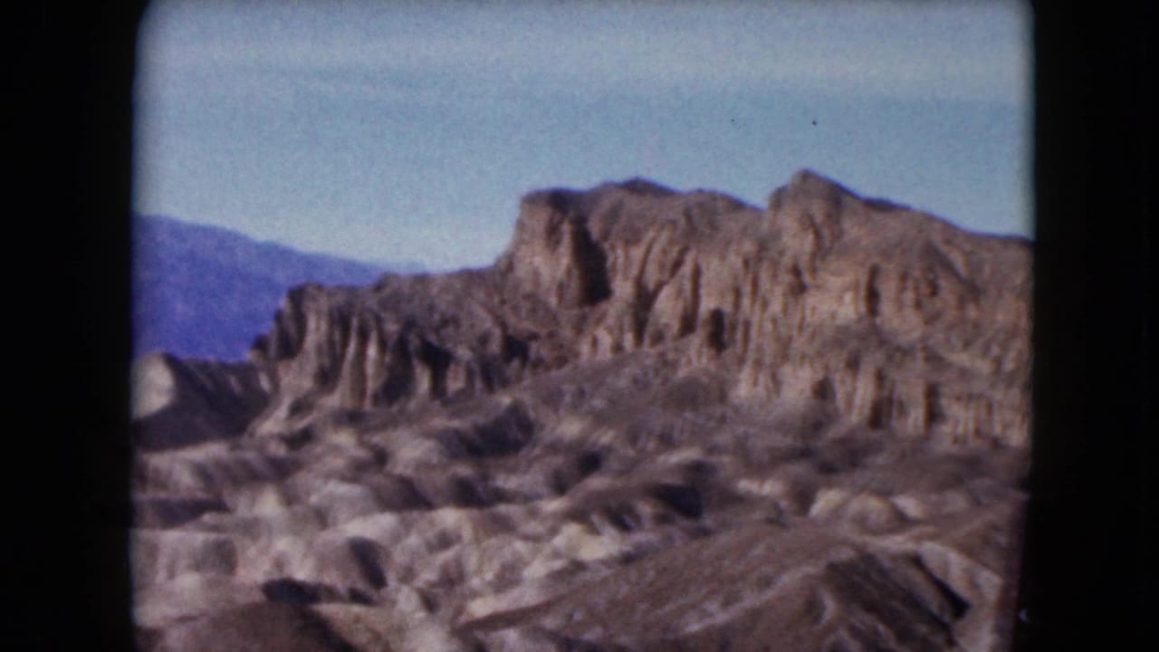 Rocky desert hills beneath a clear blue sky with dark 8mm frame edges.