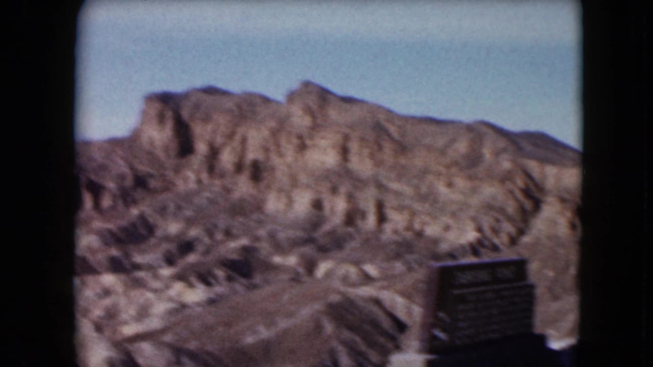 Desert rock formations with a dark roadside sign or marker at the right edge.