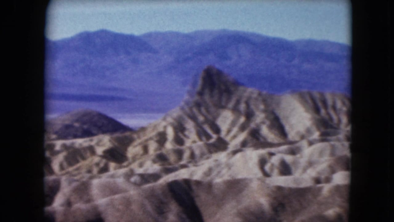 Jagged desert rock formation with layered mountains in the background.