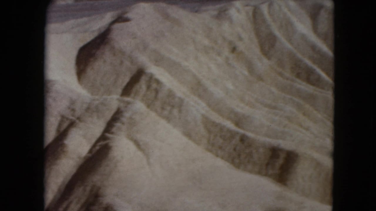 Close view of rippled sand with diagonal ridges and darker shadowed bands.