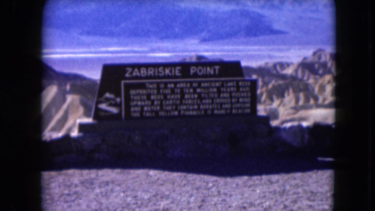 1961 8mm view of the Zabriskie Point sign, its white text, and the rugged desert terrain beyond.