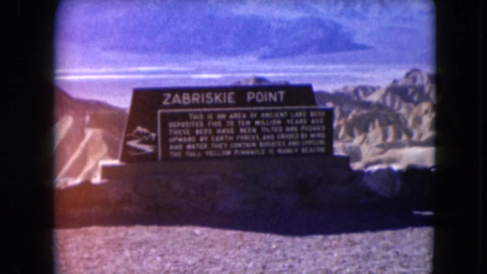 1961 8mm frame of the Zabriskie Point sign and desert hills, with warm flare and grain visible in the scan.