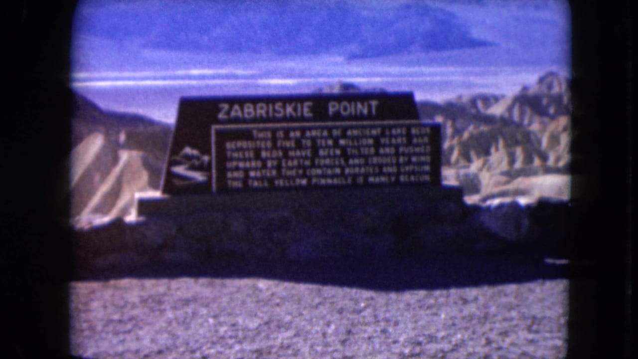 1961 8mm view of the Zabriskie Point interpretive sign at Death Valley with badlands behind it.