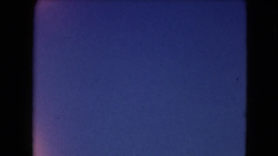 Blue transitional film frame from 1961 8mm footage, with dark gate edges and visible film texture.