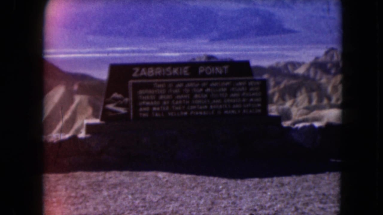 Zabriskie Point sign in front of desert hills and blue sky.