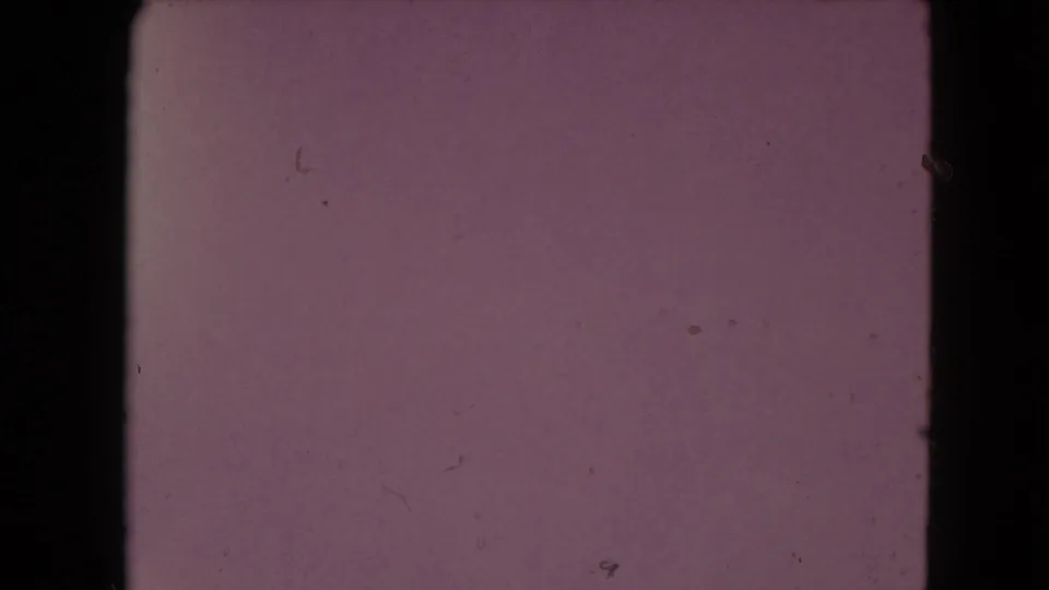 End-of-roll style 8mm frame from the Nevada clip, mostly purplish and dark with faint surface marks and minimal landscape detail.