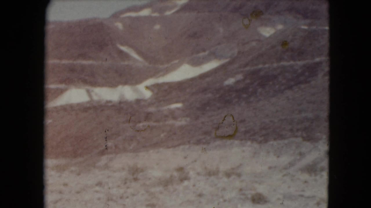 Rocky mountain slope with snow streaks and visible film wear.