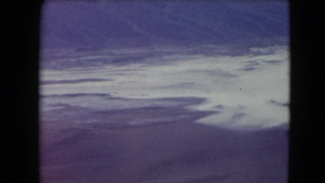 1961 Nevada 8mm aerial view showing pale waterway or salt-flat forms against soft purple desert terrain.