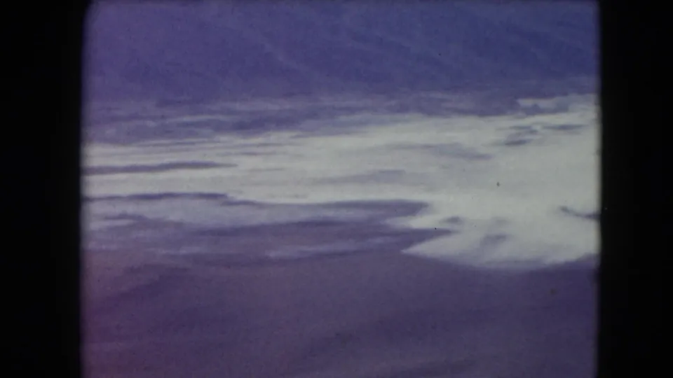 1961 Nevada 8mm aerial view showing pale waterway or salt-flat forms against soft purple desert terrain.