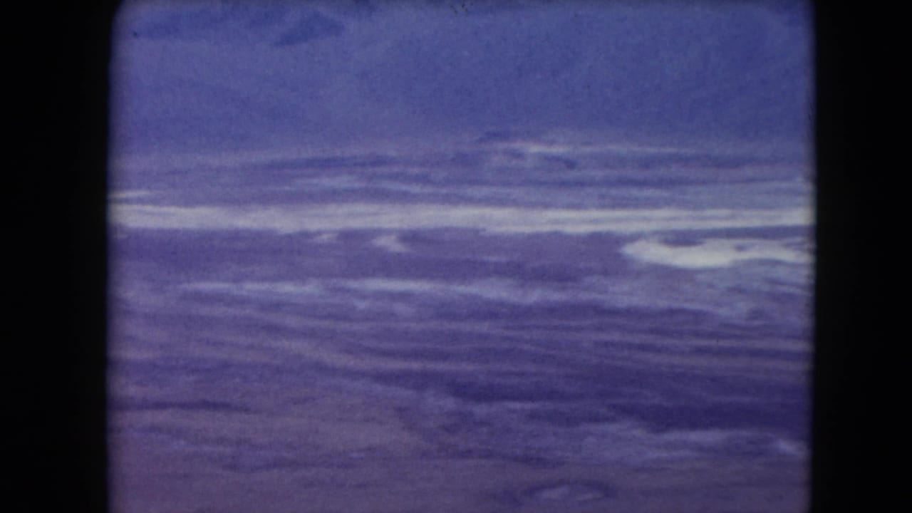 1961 8mm frame of broad blue-purple water beneath a distant horizon, with no people or structures visible.