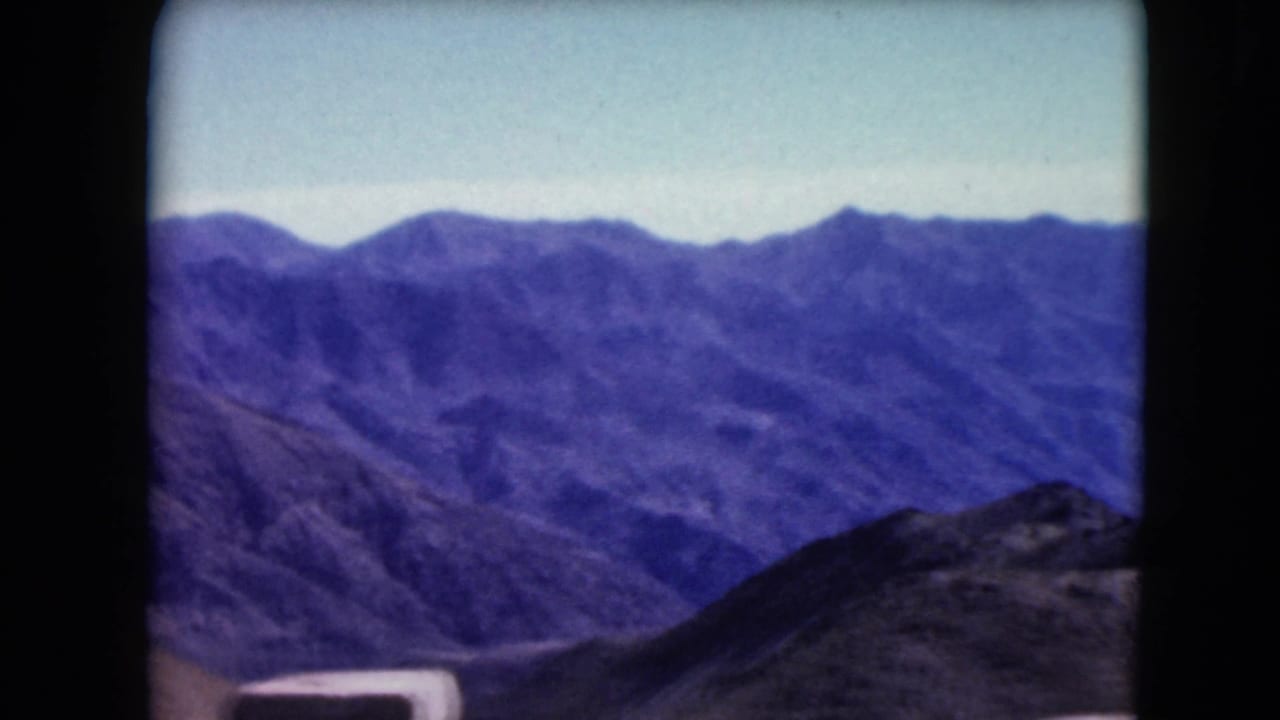 Blue-toned mountain ridges seen through rounded 8mm film borders.