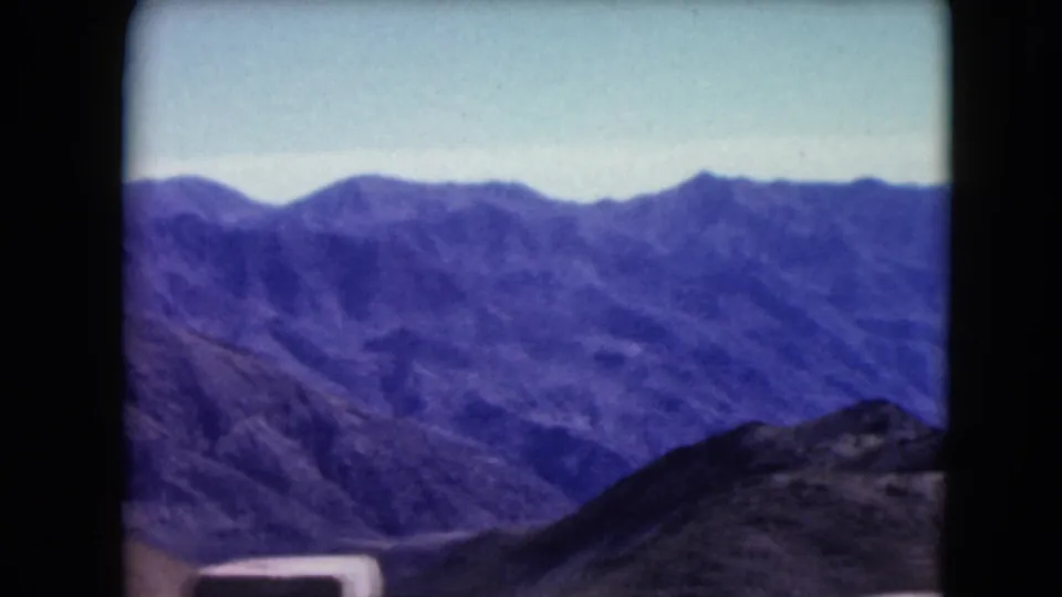1961 8mm view from Dante's View area showing layered Death Valley mountain ridges with soft focus and dark film edges.