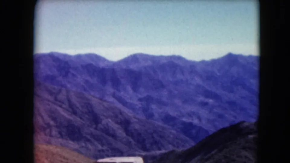 A wide Nevada landscape view shows layered purple mountain ridges and a valley under clear sky in 1961 8mm footage.