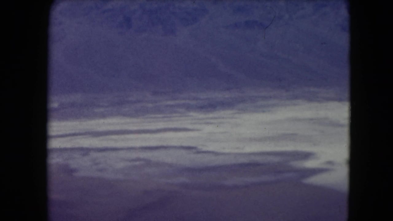 Purple-blue sky above a pale barren plain with dark film borders.