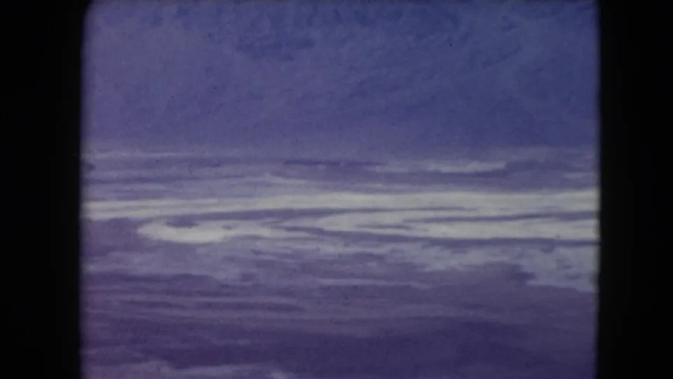 1961 Nevada 8mm view of a barren horizontal plain, pale ground bands, and a color-shifted blue-purple sky.