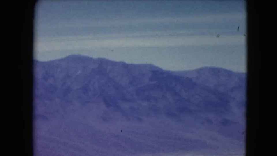 1961 Nevada 8mm view of a distant mountain range under pale sky, with aged color shift and film gate edges.