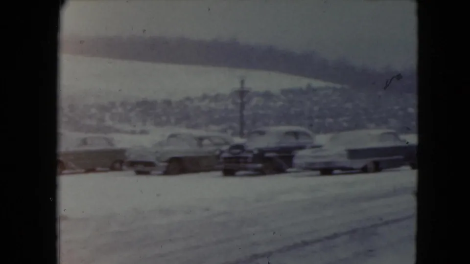 1961 Nevada 8mm frame showing classic cars parked in snow with distant hills behind them.