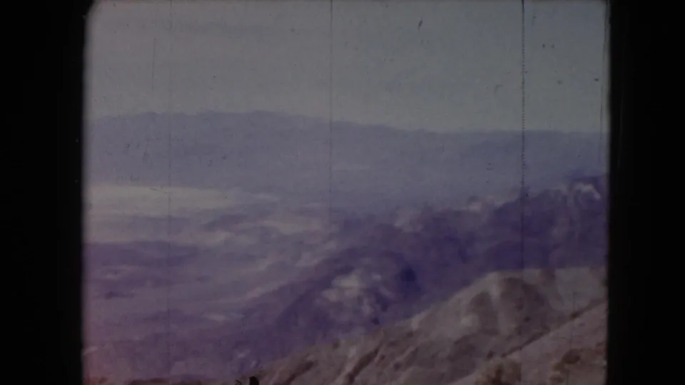 1961 Nevada 8mm frame showing a winter mountain vista from a roadside viewpoint.
