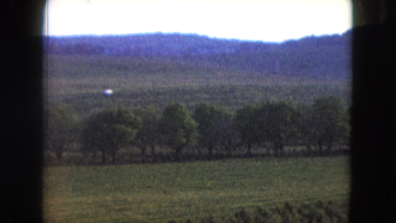 1961 Nevada rural landscape with a green field, clustered trees, hazy blue ridge, and overexposed sky.