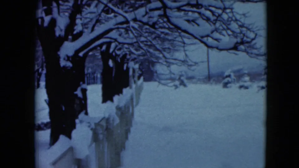 1961 Jamestown, Wisconsin home-movie frame showing a snowy fence line, bare trees, and a quiet winter path.
