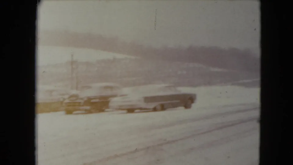 A snowy Jamestown, Wisconsin road shows several early-1960s cars in soft, faded 8mm color.