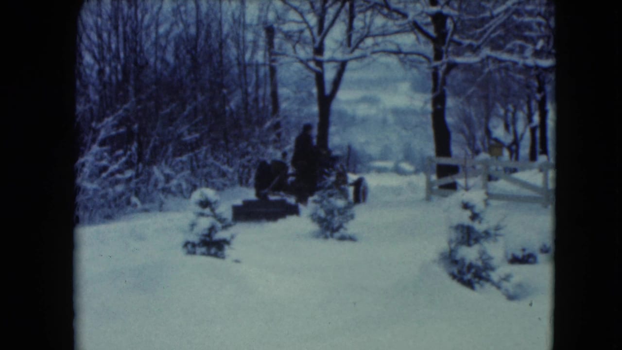 The tractor advances slowly through a snowy Jamestown, Wisconsin landscape, framed by leafless trees and a white fence.