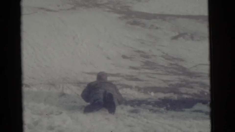 Distant bundled figure on a snowy or icy field in Camden, New Jersey, from 1961 8mm home-movie footage.