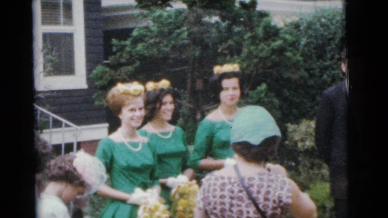 Bridesmaids in green dresses stand outdoors while guests and a photographer-like figure gather nearby.