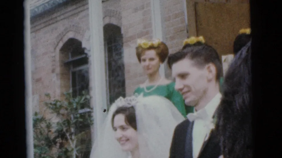 Bride and groom at a Camden church wedding in 1961, framed by bridesmaids and partly obscured by a foreground figure.