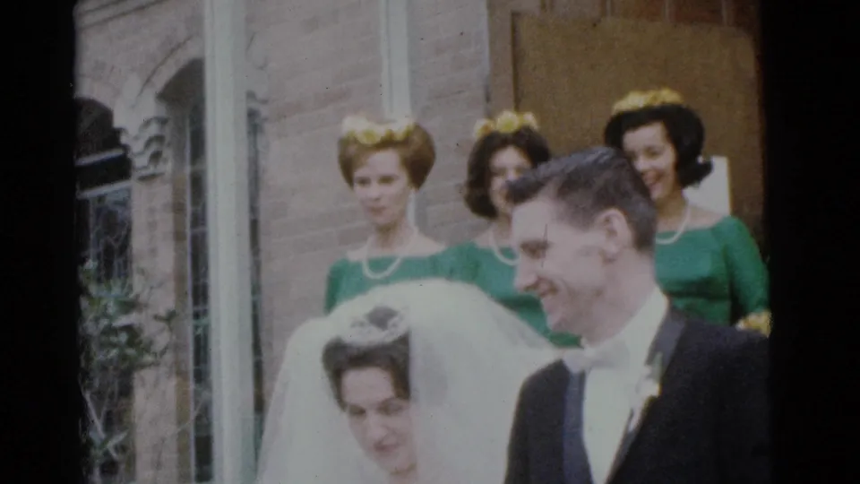 The bride and groom smile outside a Camden brick church in 1961, with bridesmaids in green dresses standing behind them.