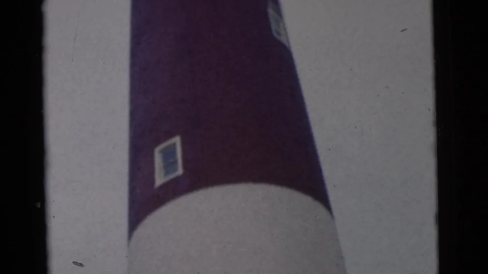 1961 8mm frame from Camden, New Jersey, showing the lower and middle portions of a red and white lighthouse from below.