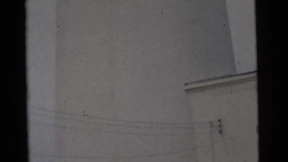 1961 Camden 8mm frame showing a close, upward view of a pale tower or lighthouse surface against a gray sky.