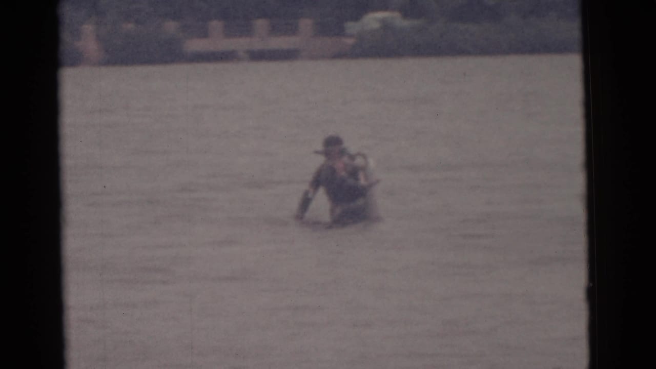 Scuba diver farther out in the water, bending forward slightly.