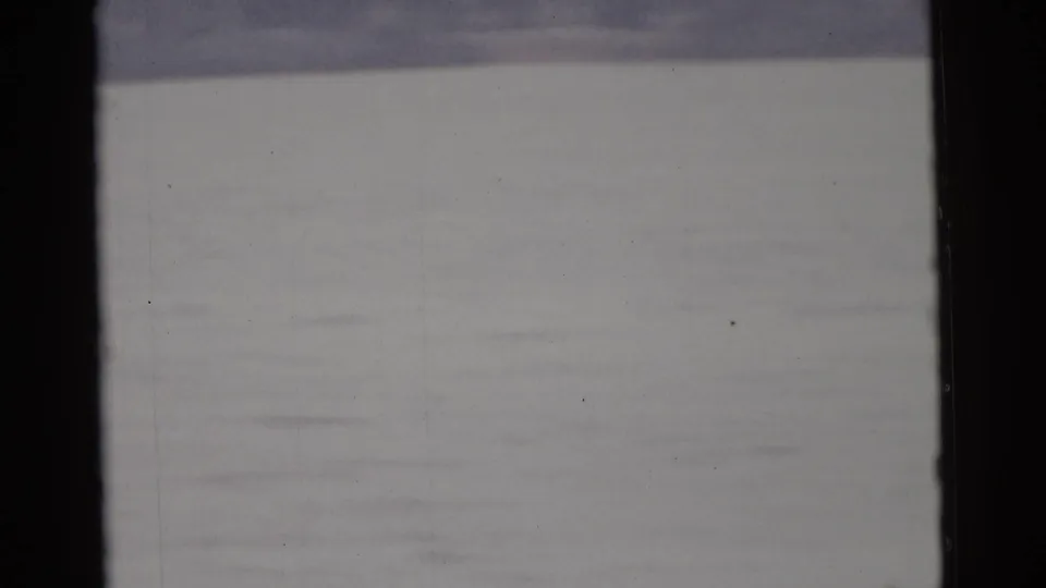 End frame from the supplied 1961 Camden clip, with pale water below a faint dark shoreline.