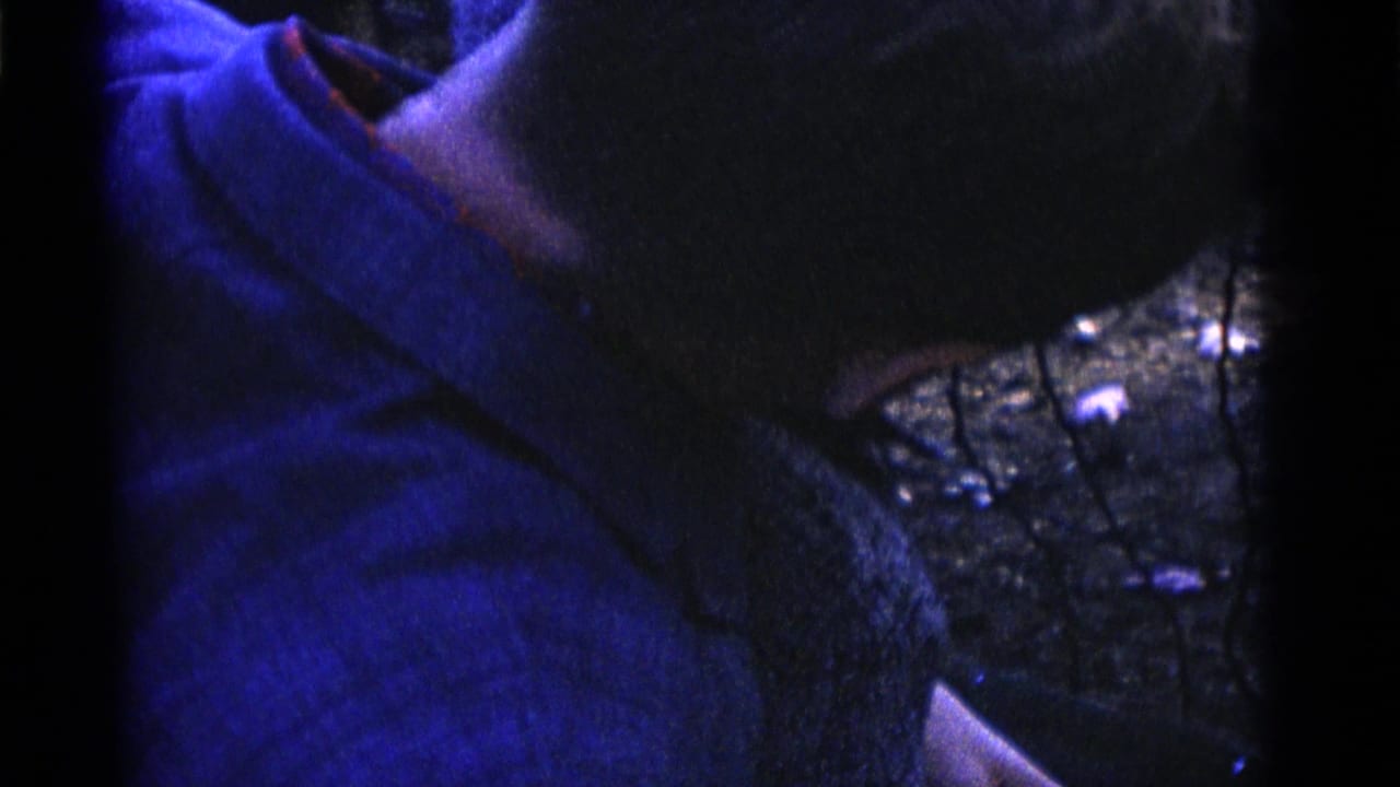 A child in a blue shirt is held close to a wire enclosure in Camden, New Jersey 1961 home-movie footage.
